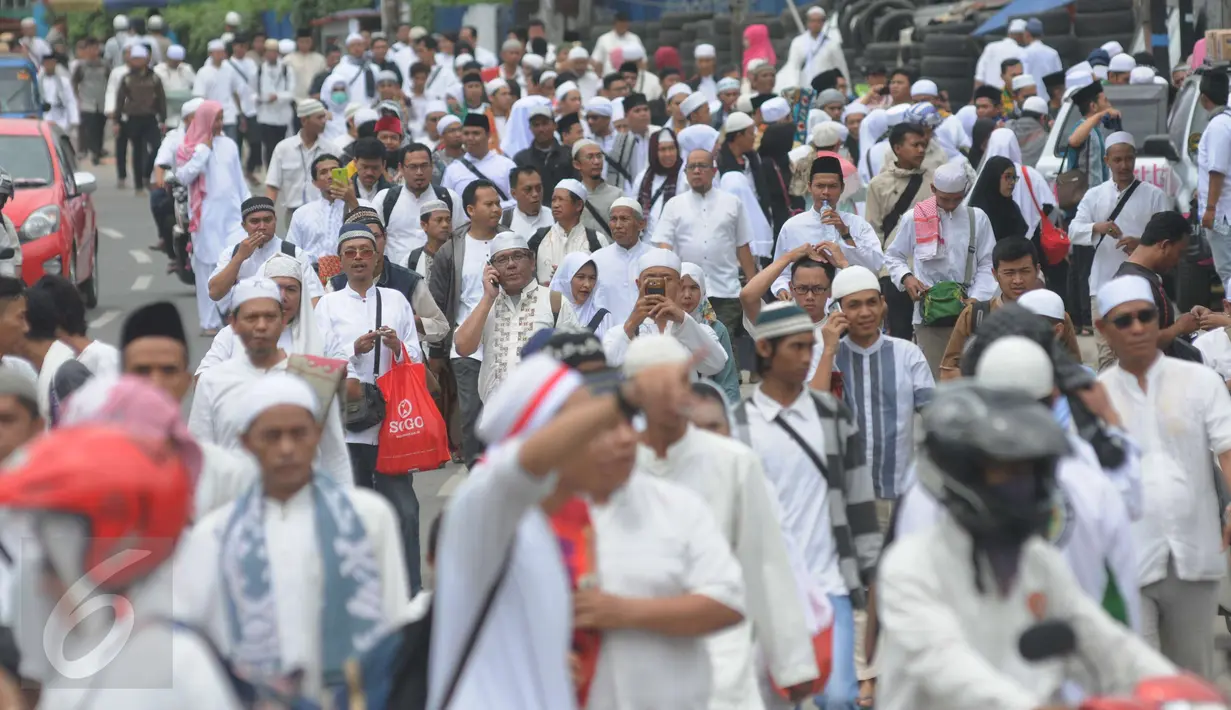 Puluhan orang berjalan kaki menuju Monas dari arah Tanah Abang, Jakarta, Jumat (2/12). Mereka terlihat berbondong-bondong berjalan untuk mengikuti demo 2 Desember di Lapangan Monas. (Liputan6.com/Helmi Afandi)