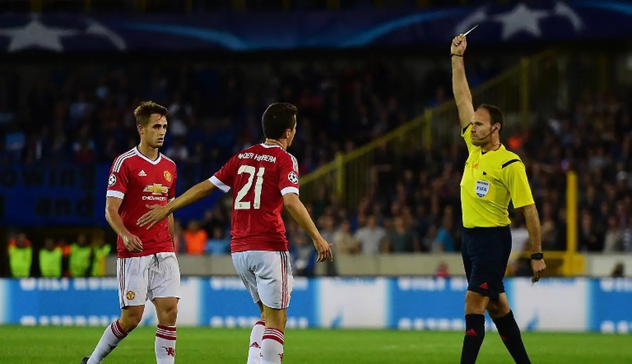 Ander Herrera menerima kartu kuning dari wasit Antonio Mateu Lahoz saat melawan Club Brugge. Kamis (27/8/2015) dini hari WIB. (AFP Photo/John Thys) 