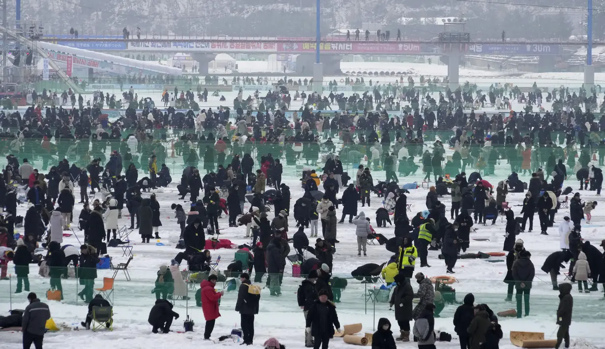 Para peserta memancing ikan trout melalui lubang yang mereka buat di atas sungai beku di Hwacheon, Korea Selatan, Sabtu (7/1/2023). Kontes ini merupakan bagian dari festival es tahunan yang menarik lebih dari satu juta pengunjung setiap tahun. (AP Photo/Ahn Young-joon)