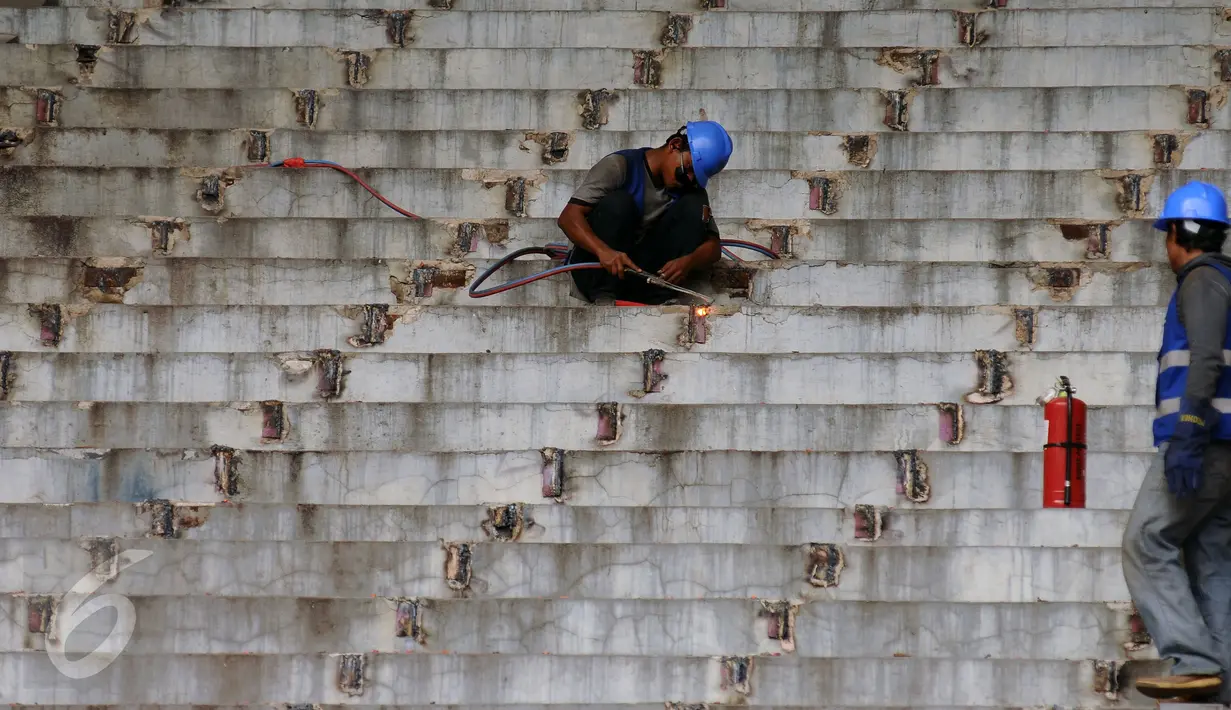 Pekerja membersihkan sisa besi penopang bangku penonton di Stadion GBK Jakarta, Selasa (18/10). Pengerjaan renovasi Stadion GBK bagian persiapan jelang Asian Games 2018 dan ditargetkan selesai Oktober 2017. (Liputan6.com/Helmi Fithriansyah)