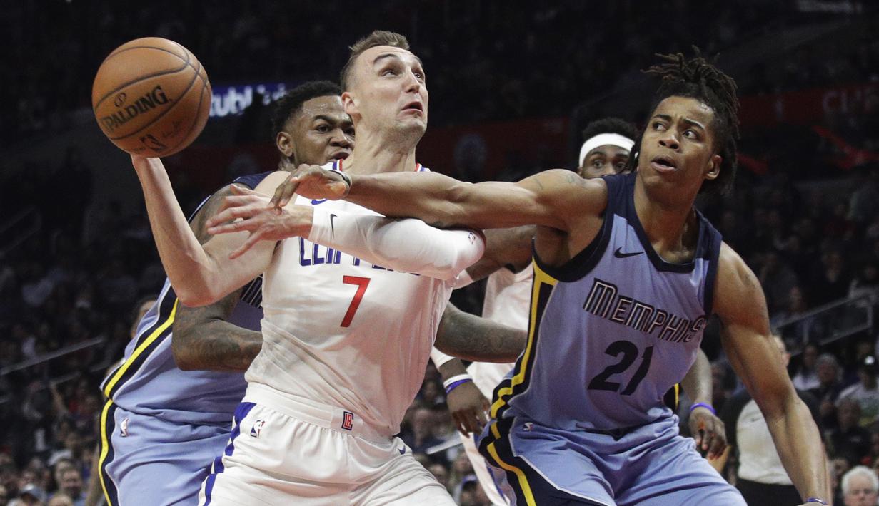 Pemain Los Angeles Clippers, Sam Dekker (kiri) berusaha mlewati adangan dua pemain Memphis Grizzlies pada laga NBA basketball game, di Staples Center, Los Angeles, (2/1/2018). Clippers menang 113-105. (AP/Jae C. Hong)