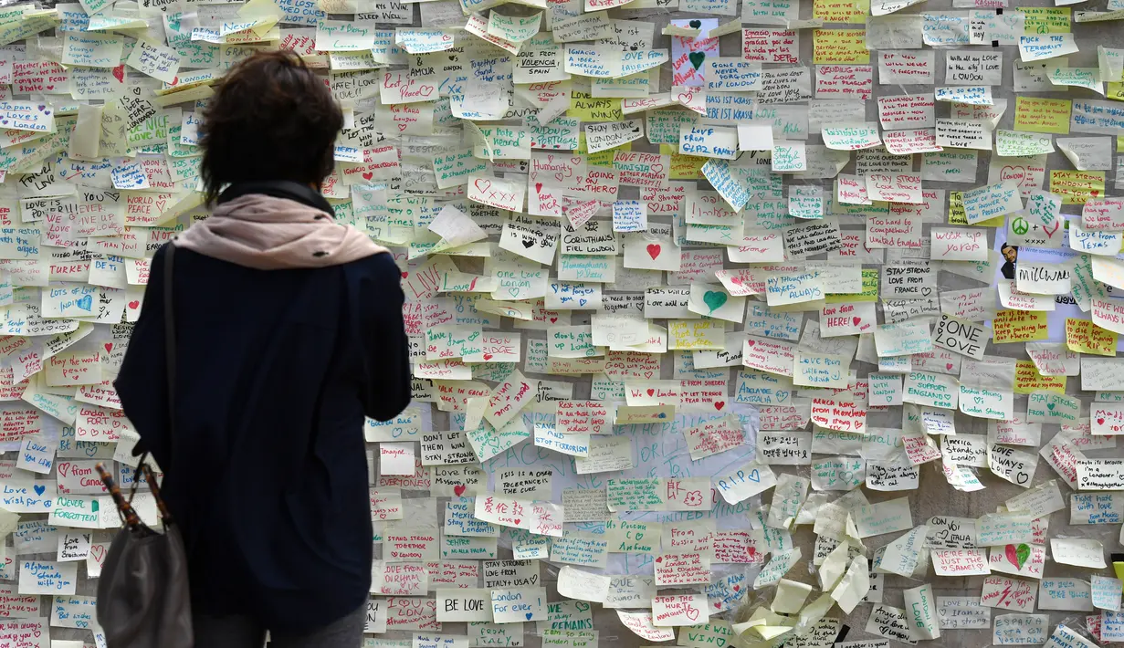 Seorang wanita melihat pesan yang ditinggalkan oleh simpatisan di jembatan London, Inggris (11/6). Seminggu yang lalu (3/6) terjadi penyerangan yang menyebabkan 7 orang tewas. (AFP PHOTO / Ben STANSALL)