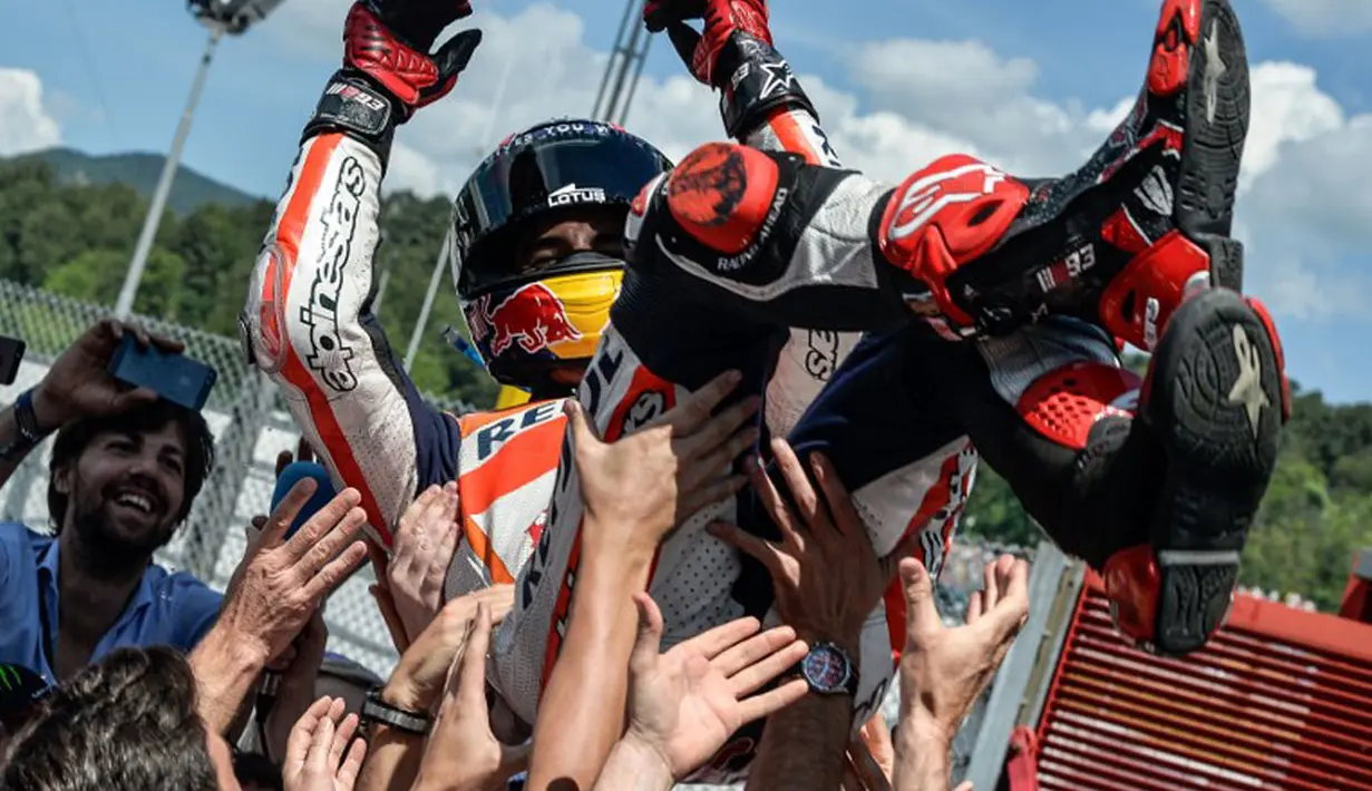 Sebelum naik ke podium, Marc Marquez (atas) merayakan kemenangan bersama tim Honda MotoGP di Sirkuit Mugello, Italia, (1/6/2014). (AFP PHOTO/Andreas Solaro)