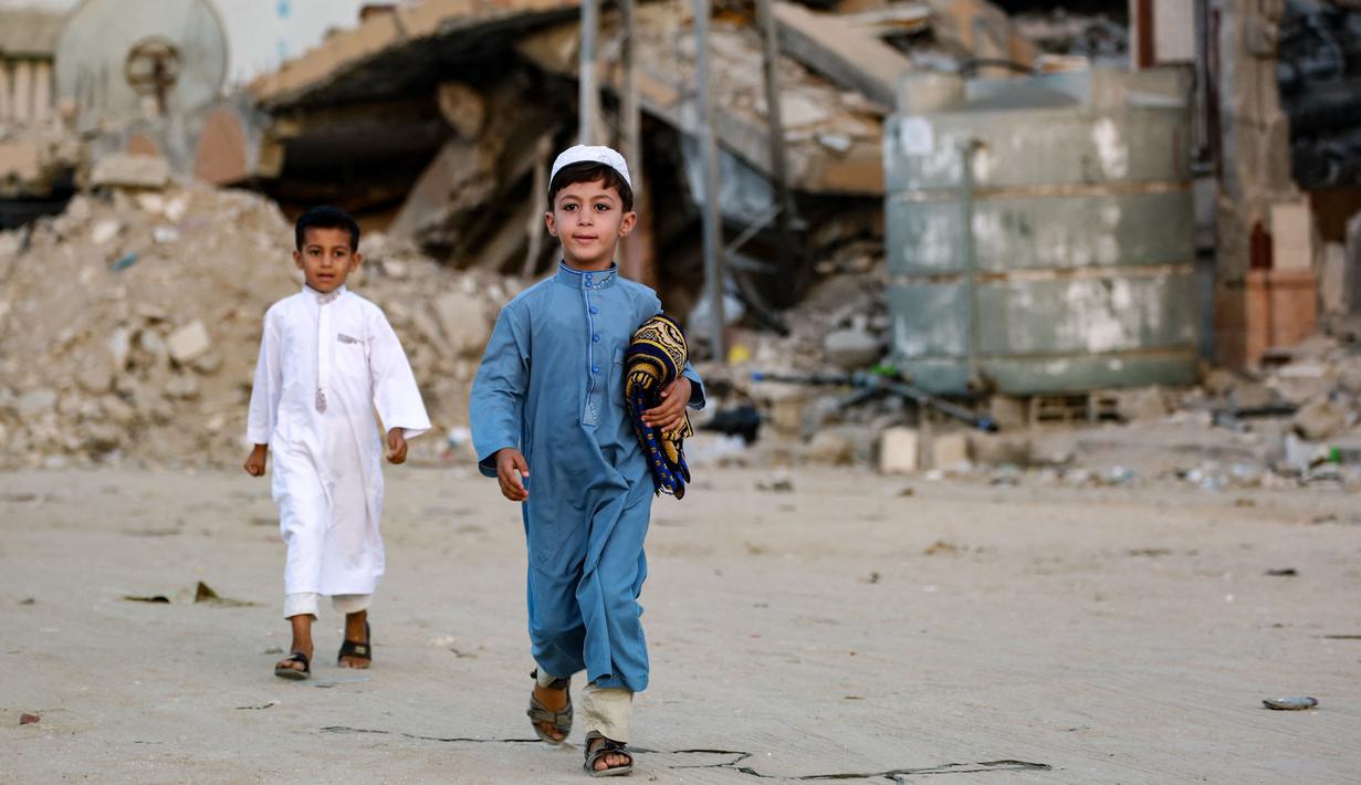 Seorang anak laki-laki Palestina membawa sajadahnya, berjalan untuk mengikuti salat Idul Adha di pagi hari di Khan Yunis di Jalur Gaza selatan, pada 16 Juni 2024. (Bashar TALEB/AFP)