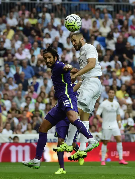 Penyerang Real Madrid, Karim Benzema (kanan) berebut bola udara dengan bek Malaga, Marcos Angeleri pada Liga Spanyol di Santiago Bernabeu, Madrid, (26/9/2015). Madrid bermain imbang atas malaga dengan skor 0-0. (AFP PHOTO/PIERRE-PHILIPPE Marcou)