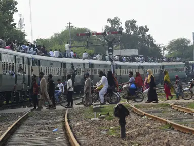 Warga Pakistan menaiki kereta api yang penuh sesak saat orang-orang melakukan perjalanan ke kampung halaman dan desa mereka untuk merayakan Idul Adha, atau "Hari Raya Kurban," di Lahore, Pakistan, Kamis (7/7/2022). Idul Adha, hari raya Islam terpenting, menandai kesediaan Nabi Ibrahim, Ibrahim untuk mengorbankan anaknya. (AFP/Arif Ali)