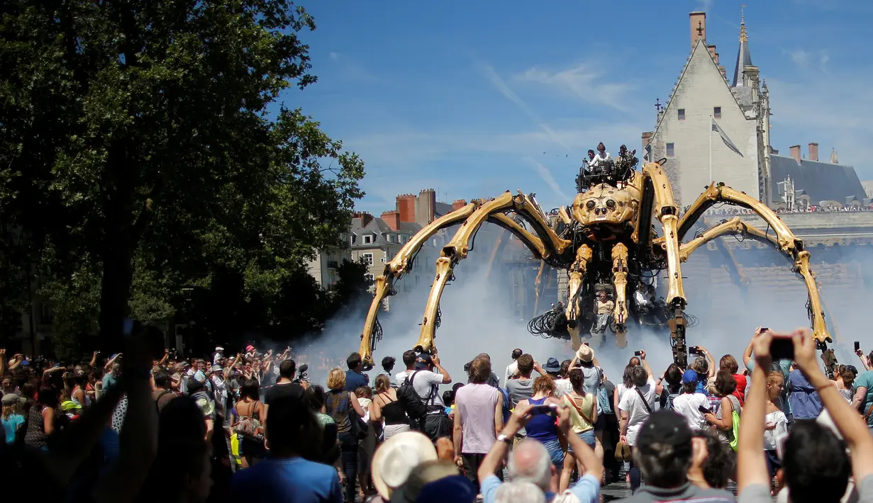 Sejumlah orang melihat robot mekanik laba-laba raksasa bernama Kumo Ni saat berjalan berkeliling Kota Nantes, Prancis, Jumat (8/7). Robot Mekanik laba-laba raksasa ini di buat oleh perusahaan La Machine. (REUTERS/Stephane Mahe)