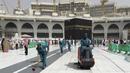 Para pekerja membersihkan Masjidil Haram saat kegiatan umrah di kota suci Muslim Mekah, Arab Saudi, Senin, (2/3/2020). Semenjak pemerintah Arab Saudi melarang kegiatan umrah, tempat paling suci umat Islam ini menjadi terlihat lebih sepi dari biasanya. (AP Photo/Amr Nabil)