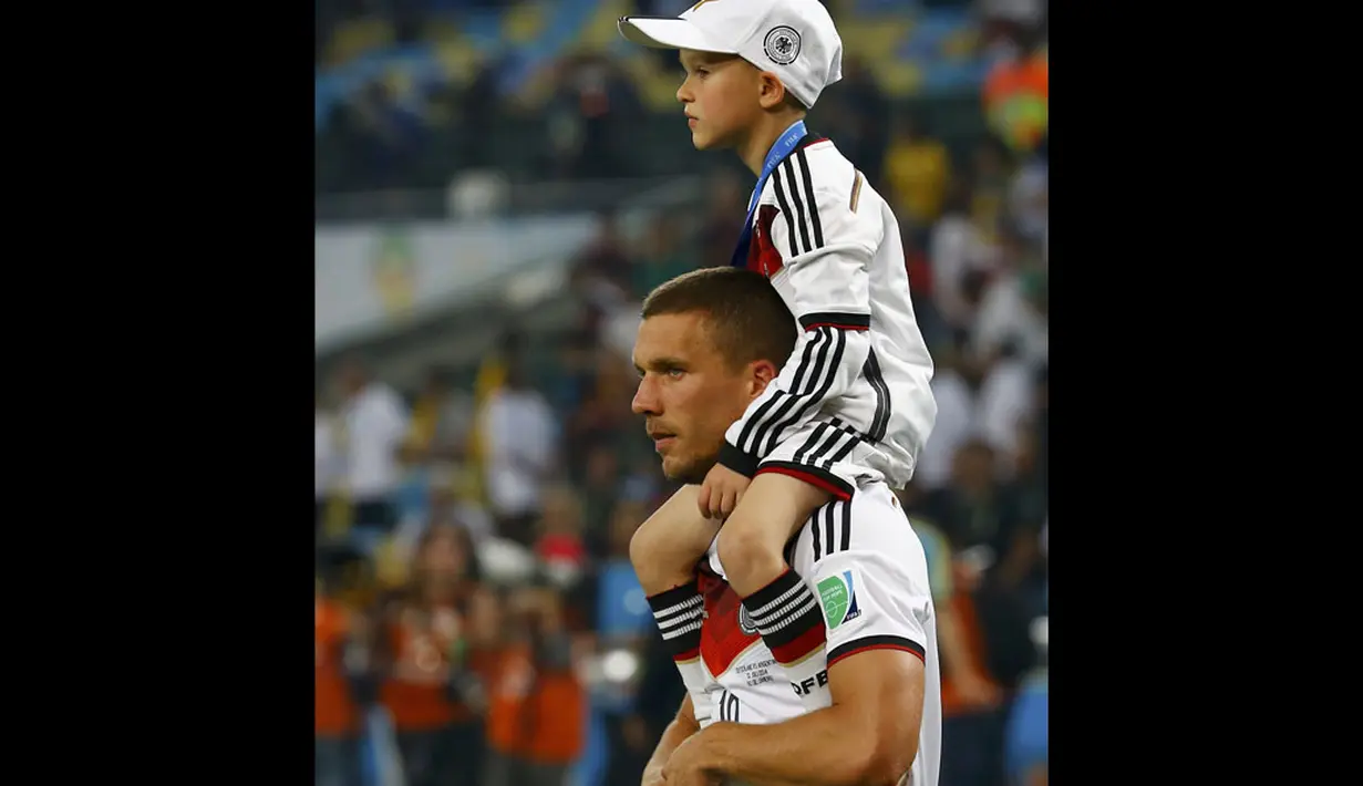 Pemain depan Timnas Jerman, Lukas Podolski, menggendong anaknya, Louis Gabriel Podolski, setelah memenangkan final Piala Dunia 2014 kontra Argentina di Stadion Maracana, Rio de Janeiro, (14/7/2014). (REUTERS/Kai Pfaffenbach)