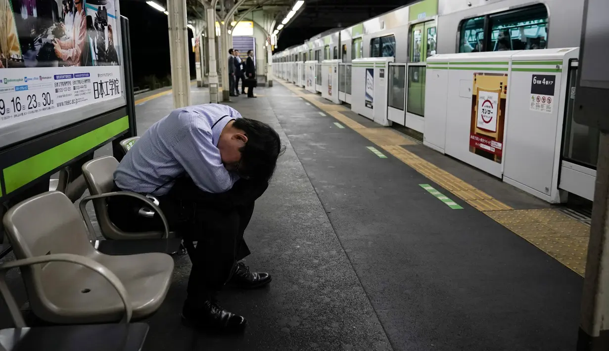 Seorang penumpang tertidur di peron saat kereta Yamanote Line melintas di Stasiun Shimbashi, Tokyo, Jepang, Sabtu (25/5/2019). (AP Photo/Jae C. Hong)