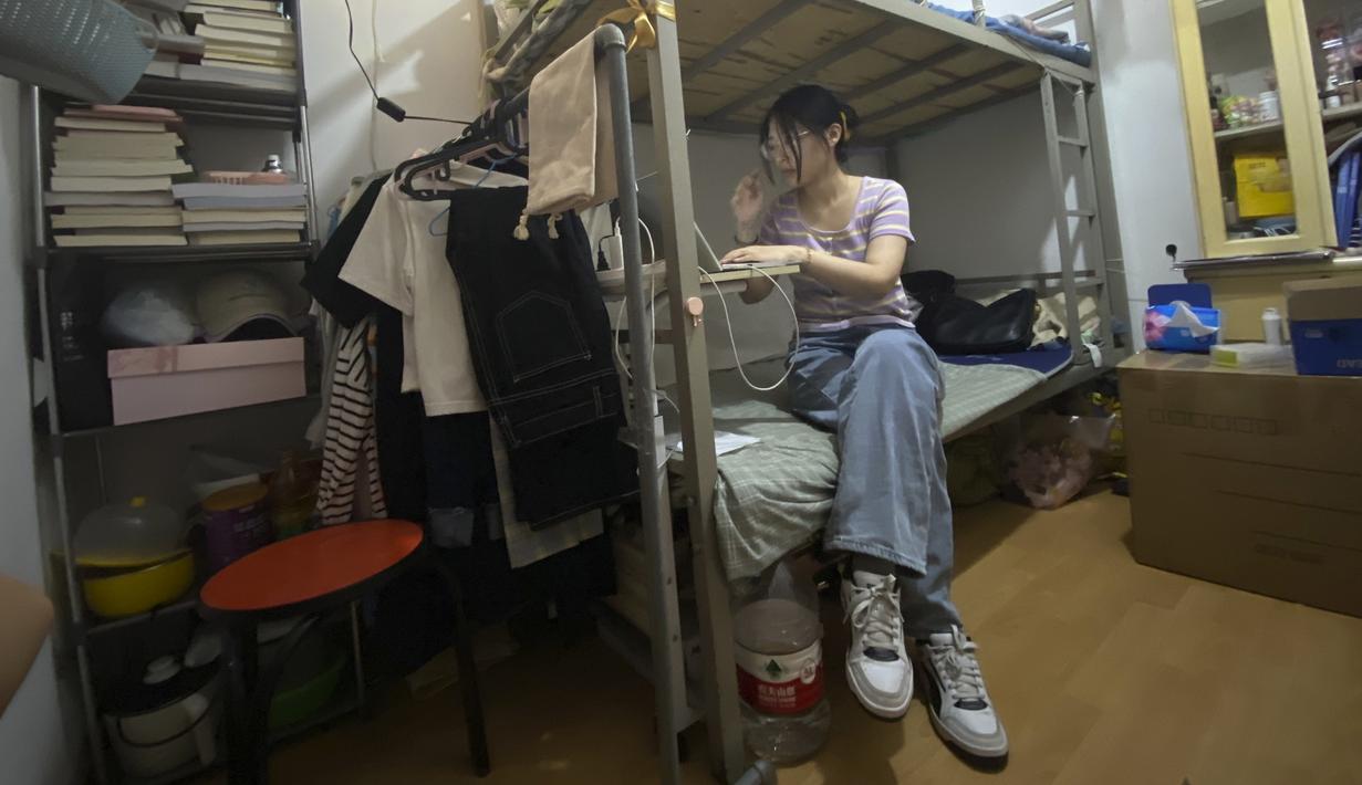 Lulusan perguruan tinggi baru-baru ini Liu Qian bekerja di komputer laptopnya di kamar yang dia sewa di sebuah apartemen di Beijing, Kamis, 7 Juli 2022.  Liu adalah salah satu dari 11 juta lulusan baru yang putus asa untuk bekerja di pasar kerja yang suram karena lockdown COVID memaksa pabrik, restoran, dan pengusaha lainnya untuk tutup. Para penyintas memotong pekerjaan dan upah. (AP Photo/Olivia Zhang)