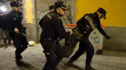 Polisi Spanyol membawa seorang pria saat bentrokan terjadi di Madrid, Spanyol, Kamis (15/3). Bentrokan berawal dari aksi protes imigran atas meninggalnya seorang pedagang jalanan asal Senegal. (AFP Photo/Olmo Calvo)