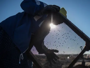 Seorang wanita lansia, Clara Maitse menyaring kotoran dan tanah saat mencari berlian di Kimberley, Northern Cape, Afrika Selatan (5/6). Clara Maitse adalah seorang wanita berusia 77 tahun yang merupakan bekas penambang ilegal. (AFP/Mujahid Safodien)