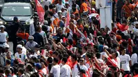 Warga menyambut kedatangan obor saat prosesi Torch Relay Asian Games 2018 di Jalan Jendral Sudirman, Jakarta, Sabtu (18/8). Hari terakhir kirab obor Asian Games ini api abadi dibawa dari Tugu Monas hingga Gelora Bung Karno. (Liputan6.com/ Fery Pradolo)