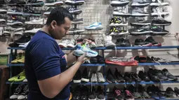 Calon pembeli saat melihat koleksi sepatu impor bekas di toko Second BJR, Kali Baru Timur, Cilincing, Jakarta Utara, Rabu (1/6/2022). Salah satunya adalah toko milik Bajuri yang telah berdiri sejak 2017, menjual berbagai jenis sepatu bermerek yang didapat dari luar negeri. (merdeka.com/Iqbal S. Nugroho)