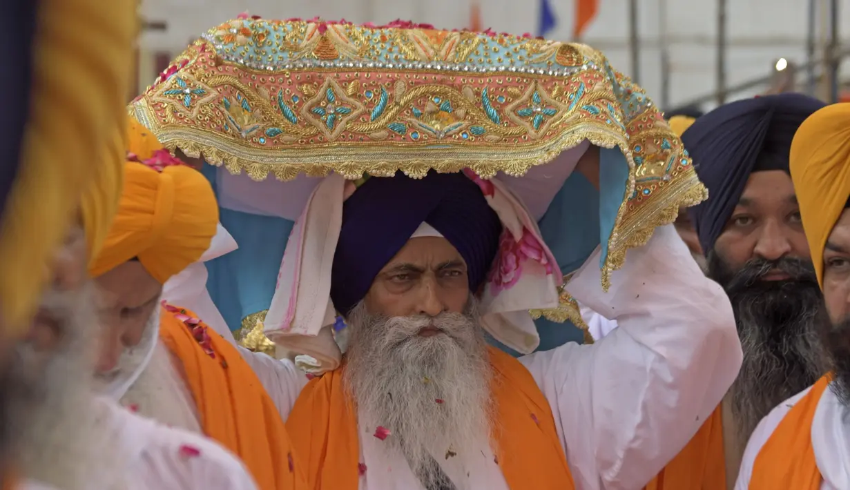 Kepala pendeta Sikh Jagtar Singh (tengah) membawa teks pokok agama Sikhisme, Guru Granth Sahib selama prosesi keagamaan dari Gurudwara Ramsar ke Akal Takht Sahib di Kuil Emas, Amritsar, India, Rabu (19/8/2020). Acara ini untuk memperingati 416 tahun pelantikan Guru Granth Sahib. (NARINDER NANU/AFP)