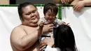 Seorang pesumo menggendong bayi sebelum dimulainya kejuaraan sumo, Honozumo, di Kuil Yasukuni, Tokyo, Senin (18/4). Selain menjadi ajang kejuaraan olahraga tradisional jepang, kejuaraan tahunan itu juga menjadi daya tarik wisata. (REUTERS/Yuya Shino)