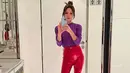 <p>Victoria dibalut outfit bernuansa kontras. Ia mengenakan atasan sweater berwarna ungu, yang dipadunya dengan plastic pants dan stiletto heels berwarna magenta. Foto: Instagram.</p>