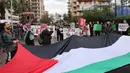 Para aktivis memegang bendera Palestina raksasa dan menutup jalan menuju kedutaan besar Mesir di ibu kota Lebanon, Beirut, pada 19 Februari 2024. (ANWAR AMRO/AFP)