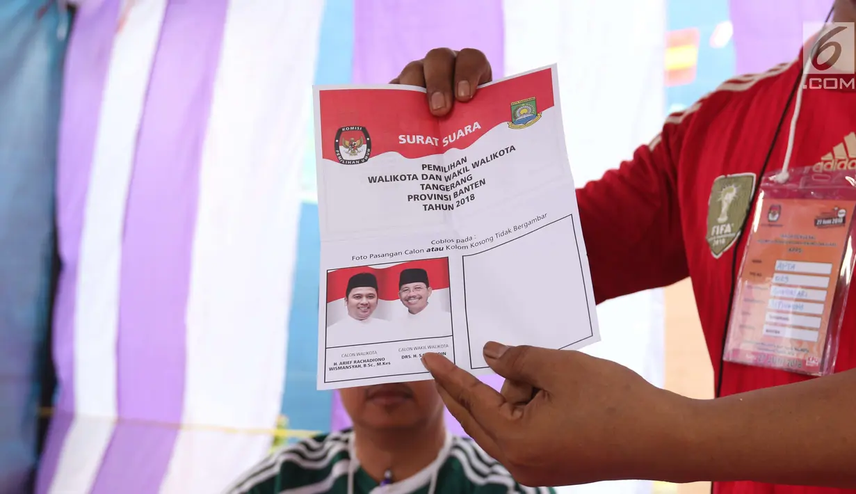 Petugas KPPS menunjukkan surat suara pada Pilkada Serentak 2018 di TPS 29 Gandasari, Kota Tangerang, Rabu (27/6). Di TPS ini warga yang menggunakan hak pilih untuk Pilkada Kota Tangerang dapat merasakan sensasi Piala Dunia 2018 (Liputan6.com/Angga Yuniar)