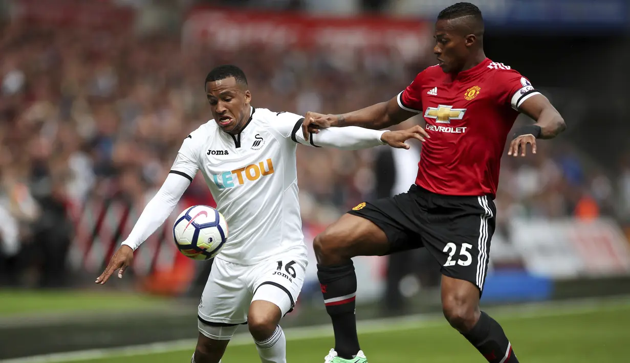Pemain Manchester United, Antonio Valencia (kanan) berebut bola dengan pemain Swansea City, Martin Olsson pada lanjutan Premier League di Liberty Stadium, Swansea, (19/8/2017). MU menang 4-0. (Nick Potts/PA via AP)