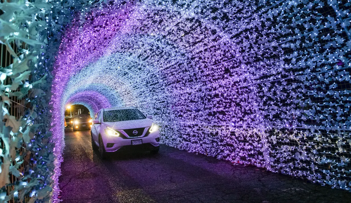 Mobil melewati terowongan cahaya dalam acara drive-thru "WinterLights" di Pacific National Exhibition, Vancouver, British Columbia, Kanada, 12 Desember 2020. Acara ini menyuguhkan berbagai instalasi cahaya, karakter, pertunjukan langsung, kuliner, serta lagu-lagu Natal. (Xinhua/Liang Sen)