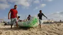 Nelayan Palestina, Mouad Abu Zeid (kanan) dan teman-temannya membawa perahu yang terbuat dari botol plastik bekas di sebuah pantai di Rafah, Jalur Gaza, 14 Agustus 2018. Zeid menggunakan 700 botol plastik bekas menjadi sebuah perahu. (AFP/SAID KHATIB)