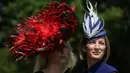 Dua wanita memakai hiasan kepala berpose saat tiba untuk menyaksikan balap kuda Royal Ascot horse di Ascot, London, (20/6). Balap kuda ini telah diadakan di Berkshire sejak tahun 1711. (AFP Photo/Daniel Leal-Olivas)