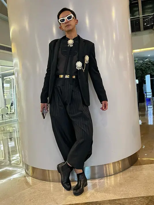 Aming kembali tampil dengan outfit serba hitam. Ia mengenakan inner berwarna hitam, ditumpuknya dengan jas hitam dan celana panjang yang juga bernuansa hitam. Sentuhan warna emas dari aksesori berupa bros dan beltnya menambah kesan mewah pada keseluruhan penampilan Aming di sini. [Foto: Instagram/amingisback]