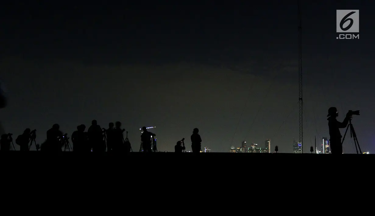 Siluet sejumlah pecinta fotografi saat mengabadikan fenomena gerhana "Super Blue Blood Moon" di atas Gedung MPR/DPR Senayan, Jakarta, Rabu Malam (31/1). (Liputan6.com/Johan Tallo)