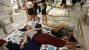 Pengunjung tidur di tempat tidur di sebuah pusat perbelanjaan menghindari panas di luar di Hangzhou, di provinsi Zhejiang timur China (24/7). Beberapa pekan terakhir China mengalami suhu udara yang cukup panas. (AFP Photo/Str/China Out)