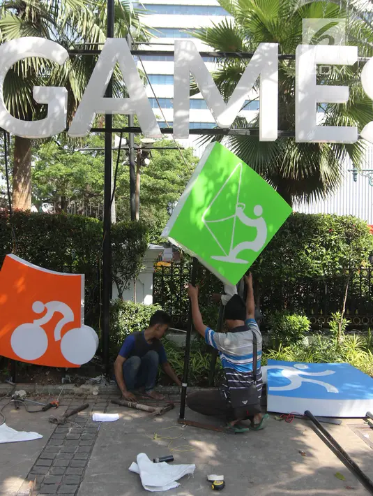 Pekerja memasang neon box Asian Games di depan Balai Kota DKI Jakarta, Jumat (6/7).Lampu neon box berwarna warni yang dipasang menggambarkan berbagai cabang olahraga yang akan dipertandingkan dalam Asian Games 2018. (Liputan6.com/Arya Manggala)