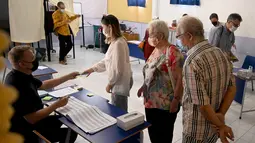 Warga Prancis mendaftar sebelum memberikan suara mereka pada putaran kedua pemilihan presiden Prancis di sebuah tempat pemungutan suara di Kerobokan, Bali, Minggu (24/4/2022). Hasil pemilu ini, nantinya akan menjadi penentu apakah Presiden Prancis Emmanuel Macron akan tetap mempertahankan jabatannya atau kehilangan posisinya tersebut. (SONNY TUMBELAKA / AFP)