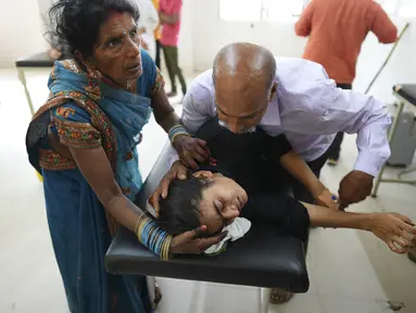 Seorang ayah mencoba menenangkan putrinya yang menderita penyakit terkait panas saat dia dibawa ke rumah sakit distrik pemerintah di Ballia, negara bagian Uttar Pradesh, India, Senin (19/6/2023). (AP Photo/Rajesh Kumar Singh)