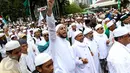 Ulama kondang Syekh Ali Jaber mengepalkan tangannya ke atas sambil mengucapkan kalimat takbir saat berjalan bersama massa aksi damai 4 November melewati Balai Kota Jakarta menuju ke Istana Merdeka, Jumat (4/11). (Liputan6.com/Faizal Fanani)