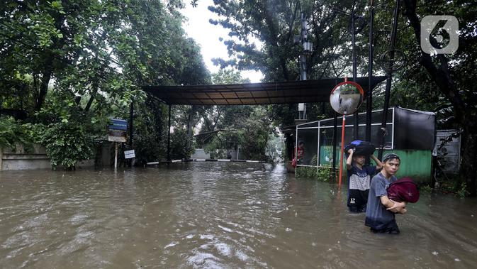 Warga melintasi banjir di Jalan Hang Lekir, Kebayoran Lama, Jakarta Selatan, Rabu (1/1/2020). Banjir tersebut disebabkan karena tingginya intensitas hujan yang mengguyur sejak Selasa (31/12/2019). (Liputan6.com/Johan Tallo)