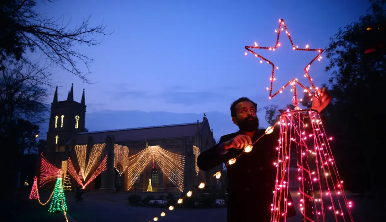 Seorang pria memasang dekorasi lampu di luar sebuah gereja di Peshawar, Pakistan barat laut (14/12/2020). Menyambut Natal, warga Pakistan mendekorasi rumah atau tempat ibadah agar lebih indah. (Xinhua/Umar Qayyum)