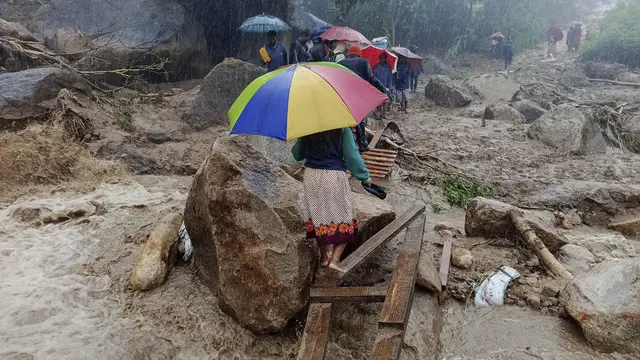 Orang-orang berjalan melintasi jembatan darurat di atas air banjir di Blantyre pada 14 Maret 2023, yang disebabkan oleh hujan lebat setelah mendaratnya topan Freddy.