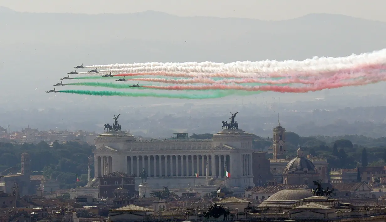 Tim aerobatik Frecce Tricolori Italia mengeluarkan asap berwarna bendera Italia saat melintas di atas Monumen Vittoriano pada militer ulang tahun Hari Republik Italia ke-72 di Roma, Sabtu (2/6). (AP Photo/Claudio Peri)