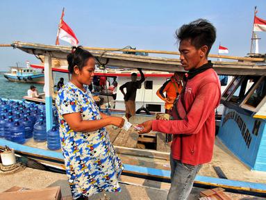 Warga kepulauan melakukan pembayaran jasa tranportasi kapal tradisional pengangkut sembako di Pulau Panjang, Banten, Sabtu (12/8/2023). Lembaga Penjamin Simpanan (LPS) terus melakukan sosialisasi sebagai upaya meningkatkan kepercayaan masyarakat terhadap industri perbankan. (Liputan6.com/Angga Yuniar)