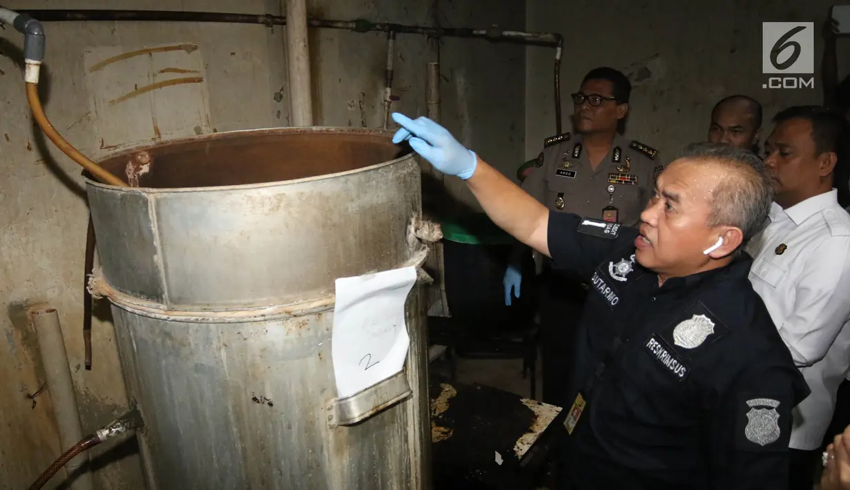 Petugas polisi dari Reskrimsus menunjukan drum tempat pembuatan ciu saat menggelar rilis di kawasan Pekojan, Tambora, Jakarta (3/5). Dari industri rumahan tersebut polisi menyita 22.000 liter bahan baku fermentasi ciu. (Liputan6.com/Arya Manggala)