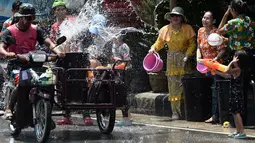 Warga menghujani pengendara sepeda motor dengan air saat merayakan Festival Songkran atau Tahun Baru Thailand di Narathiwat, Thailand, 13 April 2019. Festival ini rutin diselenggarakan setiap tanggal 13-15 April setiap tahunnya. (Madaree TOHLALA/AFP)