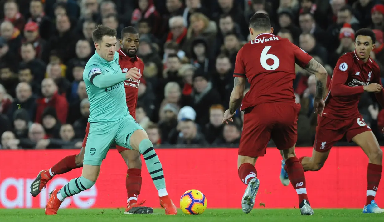 Gelandang Arsenal, Aaron Ramsey menggiring bola dari kawalan tiga pemain Liverpool selama pertandingan melawan Arsenal pada lanjutan Liga Inggris di Anfield Stadium (29/12). Liverpool menang telak atas Arsenal 5-1. (AP Photo/Rui Vieira)