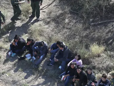 Petugas menangkap imigran Meksiko yang berusaha menyeberangi perbatasan AS-Meksiko di McAllen, Texas (3/1). Ribuan imigran masuk secara ilegal melintasi perbatasan mencari suaka di AS jelang pelantikan AS Donald Trump. (AFP Photo/John Moore/Getty Images)