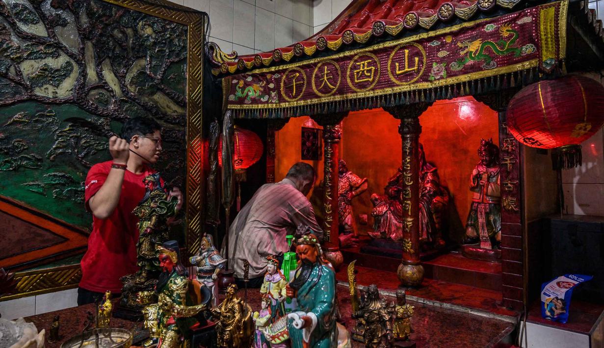 Pembersihan dilakukan dengan sangat hati-hati menggunakan kain lembut untuk menjangkau lekukan detail pada patung. Tampak dalam foto, para sukarelawan membersihkan patung-patung dewa di Kuil Hong San Ko Tee, Surabaya, Jawa Timur, pada Rabu 11 Februari 2026. (JUNI KRISWANTO/AFP)