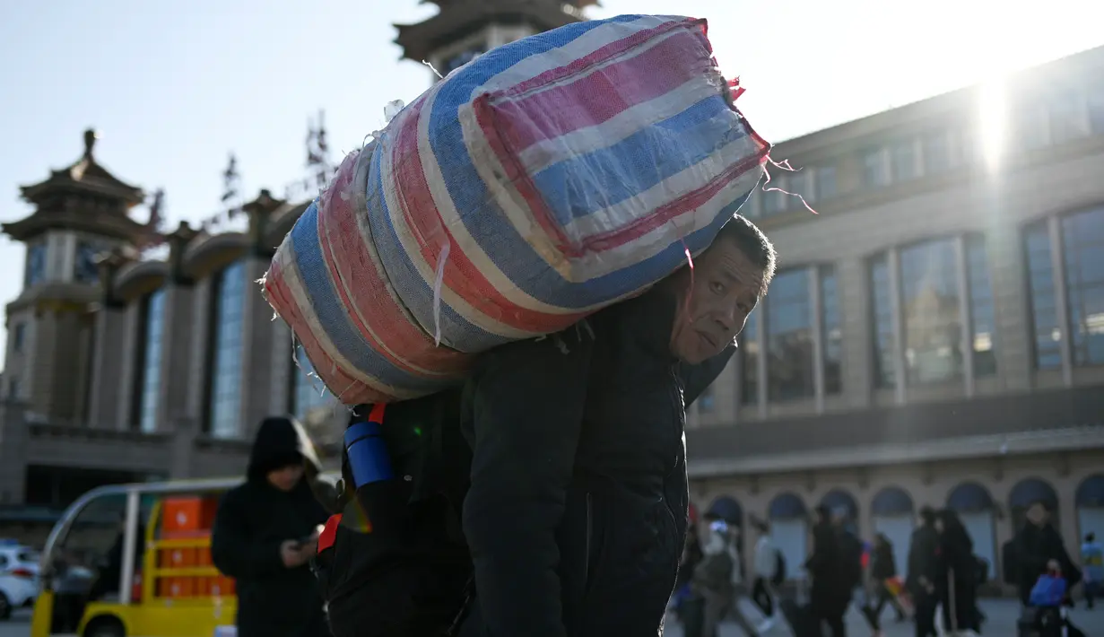 Seorang pria memanggul tas bawaannya menuju stasiun kereta api Beijing, Jumat (10/1/2020). Puluhan ribu warga China telah memulai migrasi manusia terbesar di dunia meninggalkan kota-kota besar menuju kampung halaman untuk merayakan Tahun Baru Imlek. (WANG ZHAO/AFP)