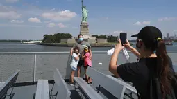 Sejumlah pengunjung berfoto dengan latar Patung Liberty di kapal pesiar yang menuju Pulau Liberty di New York, Amerika Serikat (AS) (20/7/2020). Pulau Liberty tempat Patung Liberty berada dibuka kembali pada Senin, meski bagian dalam area patung dan museum masih ditutup untuk umum. (Xinhua/Wang Ying