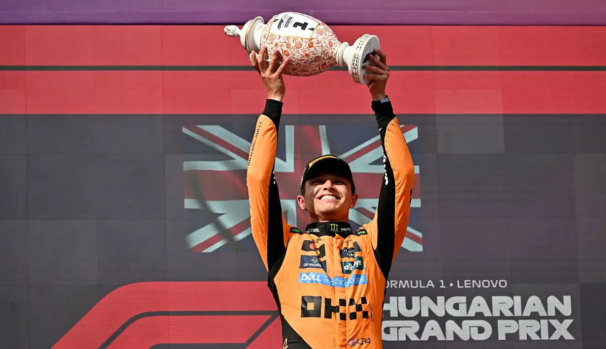 Pembalap McLaren, Lando Norris mengangkat trofi juara saat merayakan kemenangan dalam ajang balap Formula 1 GP Hungaria 2025 di sirkuit Hongaroring, Minggu (03/08/2025) waktu setempat. (AFP/Attila Kisbenedek)