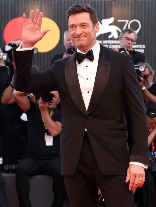 Hugh Jackman berpose untuk fotografer setibanya di pemutaran perdana film 'The Son' selama Festival Film Venesia edisi ke-79 di Venesia, Italia, Rabu (8/9/2022). Aktor tampan tersebut terlihat tersenyum sambil mengangkat tangannya, menyapa media dan penonton yang hadir. (Joel C Ryan/Invision/AP)