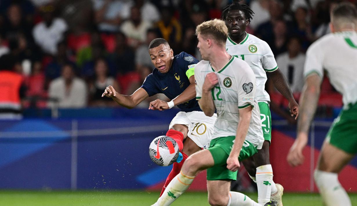 Striker Timnas Prancis, Kylian Mbappe (kiri) melepaskan tendangan yang berusaha diblok seorang pemain Republik Irlandia pada laga Grup B Kualifikasi Euro 2024 di Parc des Princes Stadium, Paris, Jumat (8/9/2023) dini hari WIB. (AFP/Miguel Medina)